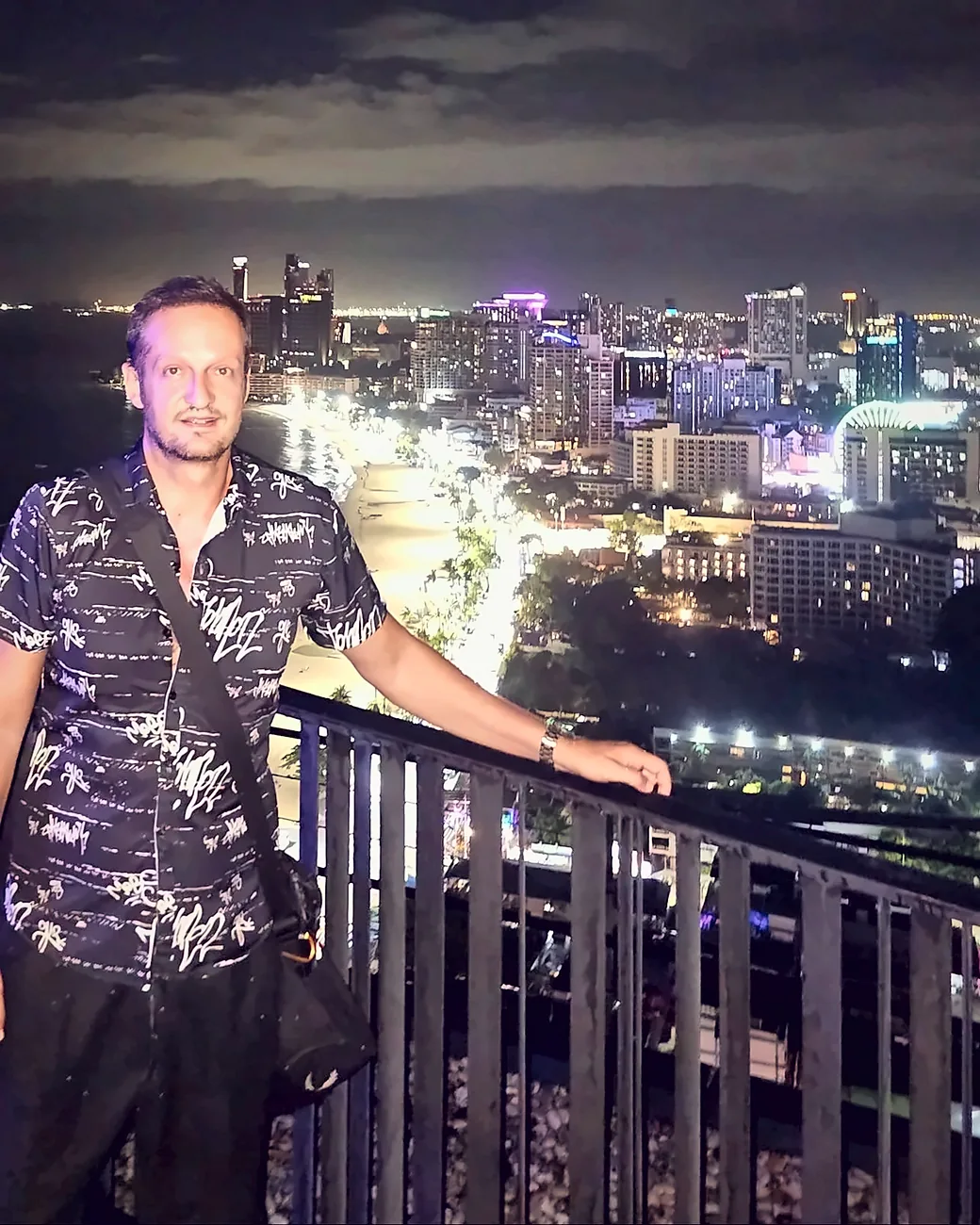 Yannis Pagiannidis at a rooftop railing above Pattaya Bay at night